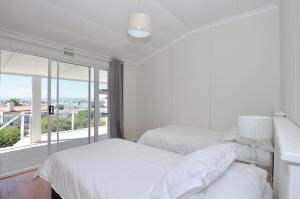 two beds in a white room with a window at Kommaweer in Yzerfontein