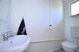 a white bathroom with a sink and a toilet at Kommaweer in Yzerfontein +30 photos