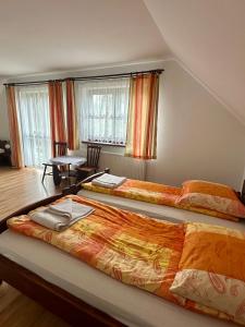 two beds in a room with a table and windows at Dolina Obiecana in Kalnica