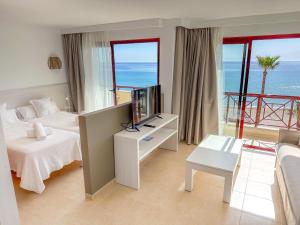 a room with two beds and a television and a balcony at Prope Mare Apartamentos in Cala Millor