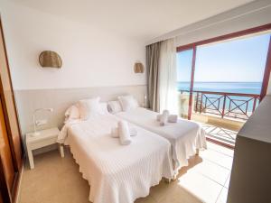 two beds in a room with a view of the ocean at Prope Mare Apartamentos in Cala Millor