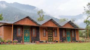 a house in a field with mountains in the background at Mhara Himachal in Bīr