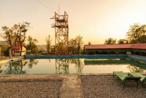a swimming pool with a tower in the background at Mhara Himachal in Bīr