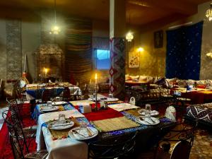 a dining room with tables and chairs in a restaurant at Les Roses Des Dunes in Merzouga
