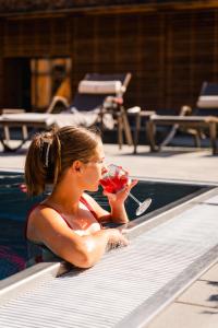 a woman in a swimming pool drinking a drink at Tirol Lodge in Ellmau +61 photos