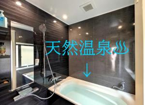 a bathroom with a tub and writing on the wall at Apt南熱海-網代 in Atami