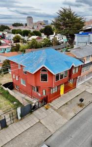 an orange house with a blue roof on a street at Haiken Hostal in Punta Arenas