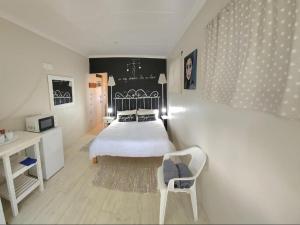 a bedroom with a bed and a table and a chair at Ocean View Drive 150 in Struisbaai