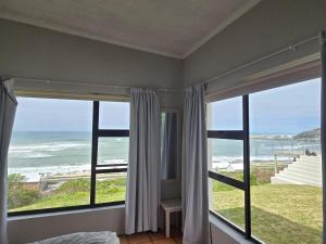 a bedroom with windows with a view of the ocean at Ocean View Drive 150 in Struisbaai