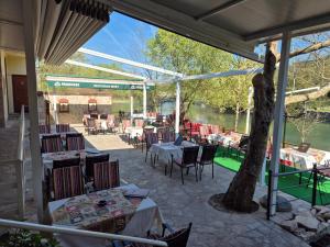 an outdoor patio with tables and chairs and a tree at Pansion & Apartments MOST Blagaj in Blagaj