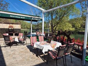a restaurant with tables and chairs and a river at Pansion & Apartments MOST Blagaj in Blagaj