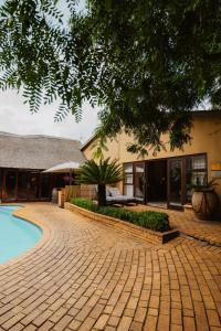 a brick walkway next to a building with a swimming pool at Greenfields Guesthouse & Restaurant in Alberton