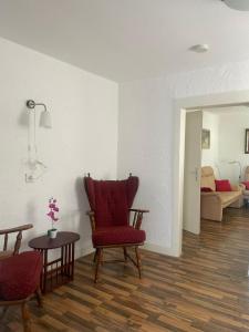 a living room with a red chair and a table at Haus Janne in Zell an der Mosel
