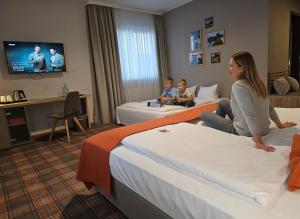 a woman and two children sitting on beds in a hotel room at Hotel Alpha in Nuremberg