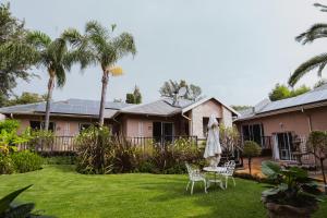a house with a yard with chairs and a table at Greenfields Guesthouse & Restaurant in Alberton