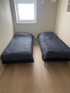 two beds sitting in a room with a window at Hybel in Porsgrunn