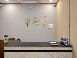 a reception desk in a lobby with a clock on the wall at Hotel Ramya Palace in Gwalior