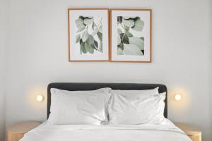 a bedroom with two framed pictures above a bed at Chic Home with BBQ & Outdoor Dining in Carnegie
