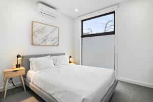 a bedroom with a white bed and a window at Chic Home with BBQ & Outdoor Dining in Carnegie +7 photos