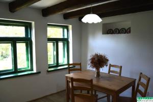 a dining room with a wooden table and windows at Chalúpka na Podkylave in Podkylava