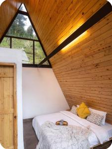 a bed in a room with a wooden ceiling at Tri peak Cottage in Jibhi +7 photos