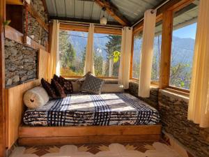 a bedroom with a bed in a room with windows at Tri peak Cottage in Jibhi