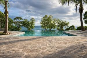a swimming pool with trees and the ocean in the background at Serenity Sands Island Glamping in Bounty Island