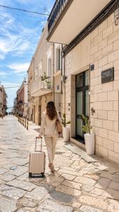 a woman walking down a street with a suitcase at Dimora in Cortile in Manfredonia