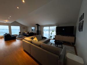 a living room with a couch and a flat screen tv at Exclusive Northernlight villa at Sørtromsøya in Tromsø