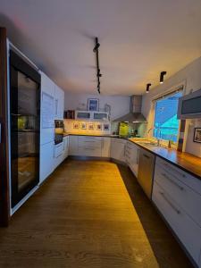 a large kitchen with white counters and a large window at Exclusive Northernlight villa at Sørtromsøya in Tromsø