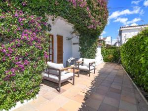 a patio with two chairs and a hedge with purple flowers at Casa Socias in Comarruga