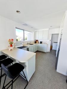 a kitchen with white cabinets and a table and chairs at 3 bedroom hidden gem in Gore