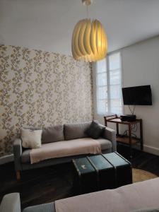 a living room with a couch and a chandelier at Nouveau - Maison de charme - Centre de Bourdeilles in Brantome en Perigord
