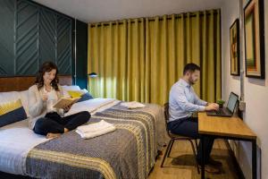 a man and a woman sitting on a bed with laptops at Latroupe Jacobs Inn in Dublin