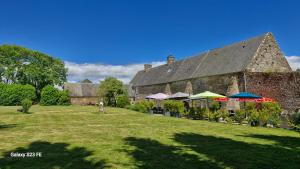 a large stone building with umbrellas in a yard at Le Relais de la Comté in Portbail
