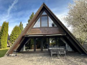 a house with a triangular roof with a table and chairs at Ferienhaus Eichhörnchennest in Waldbrunn