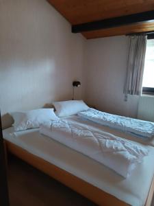 a large white bed in a bedroom with a window at Ferienhaus Katzenbuckelblick in Waldbrunn +12 photos