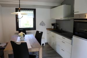 a kitchen with a wooden table and a kitchen with white cabinets at Ferienhaus Krappennest in Waldbrunn