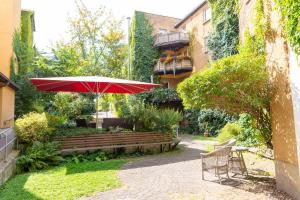 a patio with a red umbrella and a bench at Hotel Marthahaus in Halle an der Saale