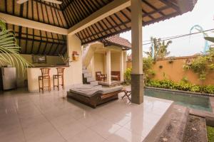 a patio with a bed and a table and chairs at Jagi Villa in Ubud