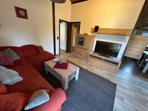 a living room with a red couch and a flat screen tv at Ferienhaus Abendstille in Waldbrunn