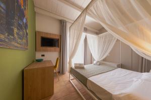 a bedroom with a bed and a desk and a window at Villa Totò Resort in Cefalù