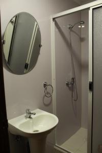 a bathroom with a sink and a shower with a mirror at Haiken Hostal in Punta Arenas