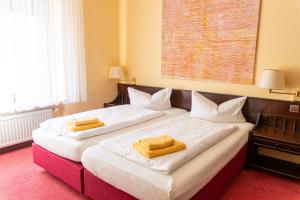 two beds in a hotel room with towels on them at Hotel Marthahaus in Halle an der Saale +28 photos