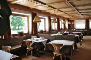 a restaurant with tables and chairs and windows at Garni Villa Linda in Corvara in Badia