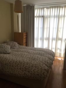a bedroom with a bed and a window with curtains at Apartamentos Ria de Foz in Foz