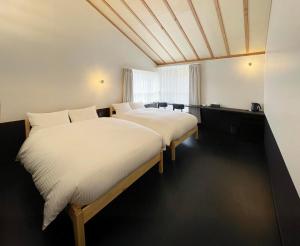 a bedroom with two beds with white sheets at Lapis Jogasaki B&B in Ito