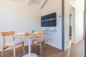 a dining room with a table and chairs and a tv at Nobel Flower Apartments in Lissone