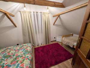 a attic room with a bed and a red rug at Agroturystyka WROTA PODLASIA in Siemiatycze