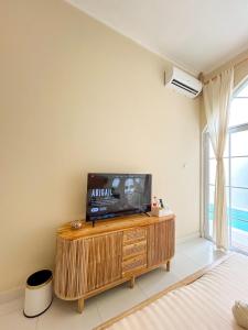 a living room with a tv on a wooden entertainment center at At Paviliun With Private Pool in Timuran